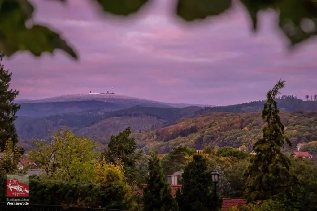 Sonnenaufgang im Herbst mit Schnee auf dem Brocken und bunter Laubfärbung in Wernigerode.