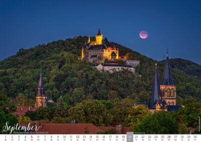 Schloss Wernigerode bei Nacht mit rotem Mond über Kirche