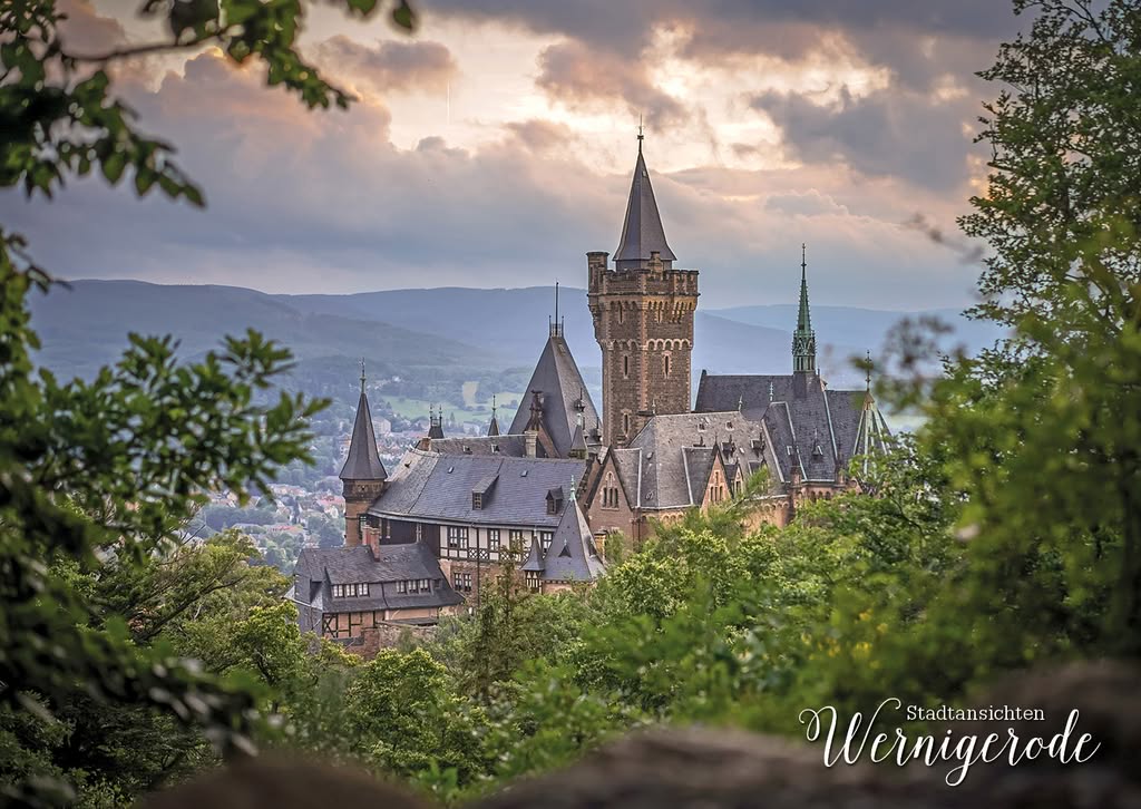 Wernigerode Castle in front of wooded Harz mountains under a dramatic sky
