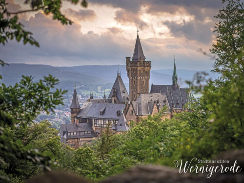 Wernigerode Castle in front of wooded Harz mountains under a dramatic sky